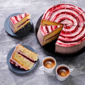 Whole layered cake with red and white swirl icing, shown with several sliced portions on plates and two cups of espresso.