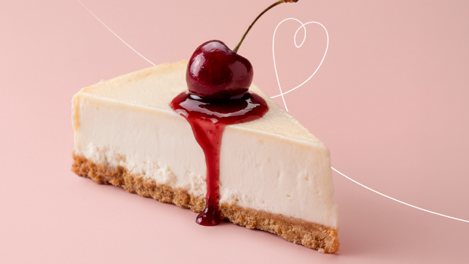 Slice of cheesecake topped with cherry and red sauce on a pastel background.