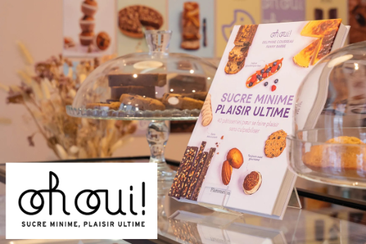 Display of pastries under glass domes with a standing Oh Oui! branded booklet in the foreground.