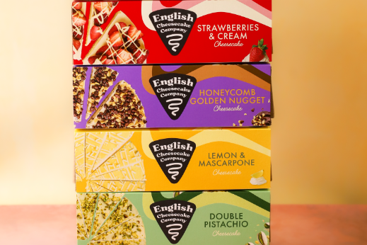 Stack of English Cheesecake Company boxes in various flavors arranged vertically against a soft yellow background.