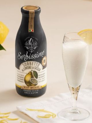Bottle of lemon sorbet drink displayed with a filled glass and fresh lemons on a light background.