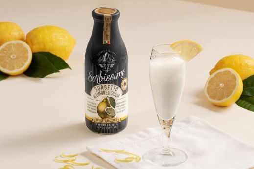 Bottle of lemon sorbet drink displayed with a filled glass and fresh lemons on a light background.