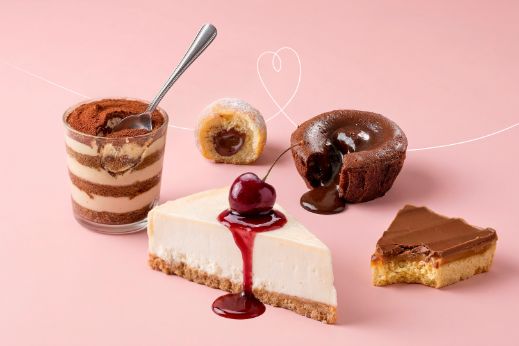 Assortment of Emmi desserts including layered tiramisu, cheesecake with cherry topping, chocolate cake and caramel pastry.