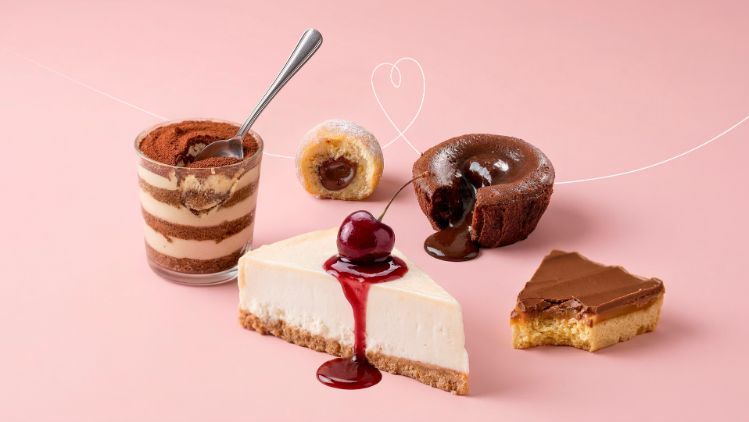 Assortment of Emmi desserts including layered tiramisu, cheesecake with cherry topping, chocolate cake and caramel pastry.