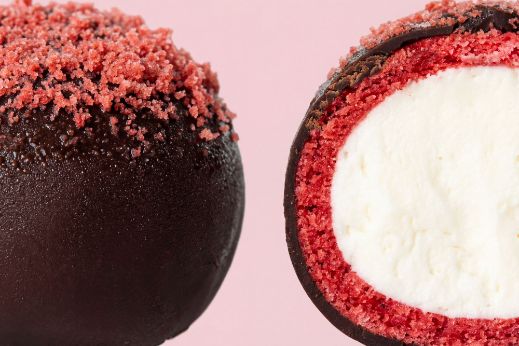 Red velvet cake pop coated in dark chocolate with red crumb topping, shown whole and in cross‑section revealing creamy white filling.